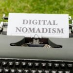 A retro typewriter outdoors with paper showing 'Digital Nomadism,' symbolizing flexible work and lifestyle.